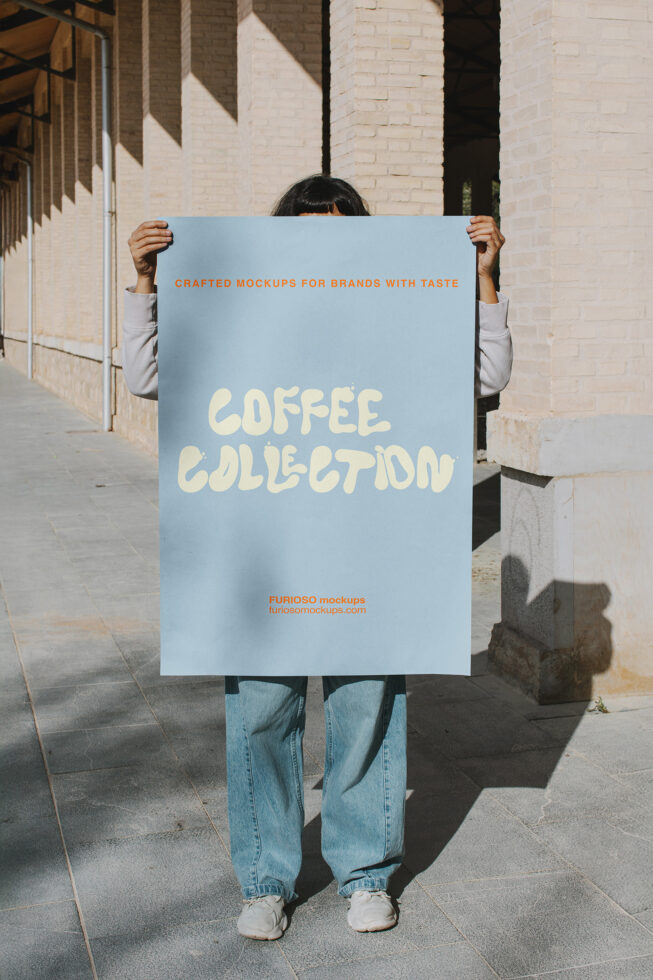 Woman holding light blue poster with cream text saying Coffee Collection in alleyway