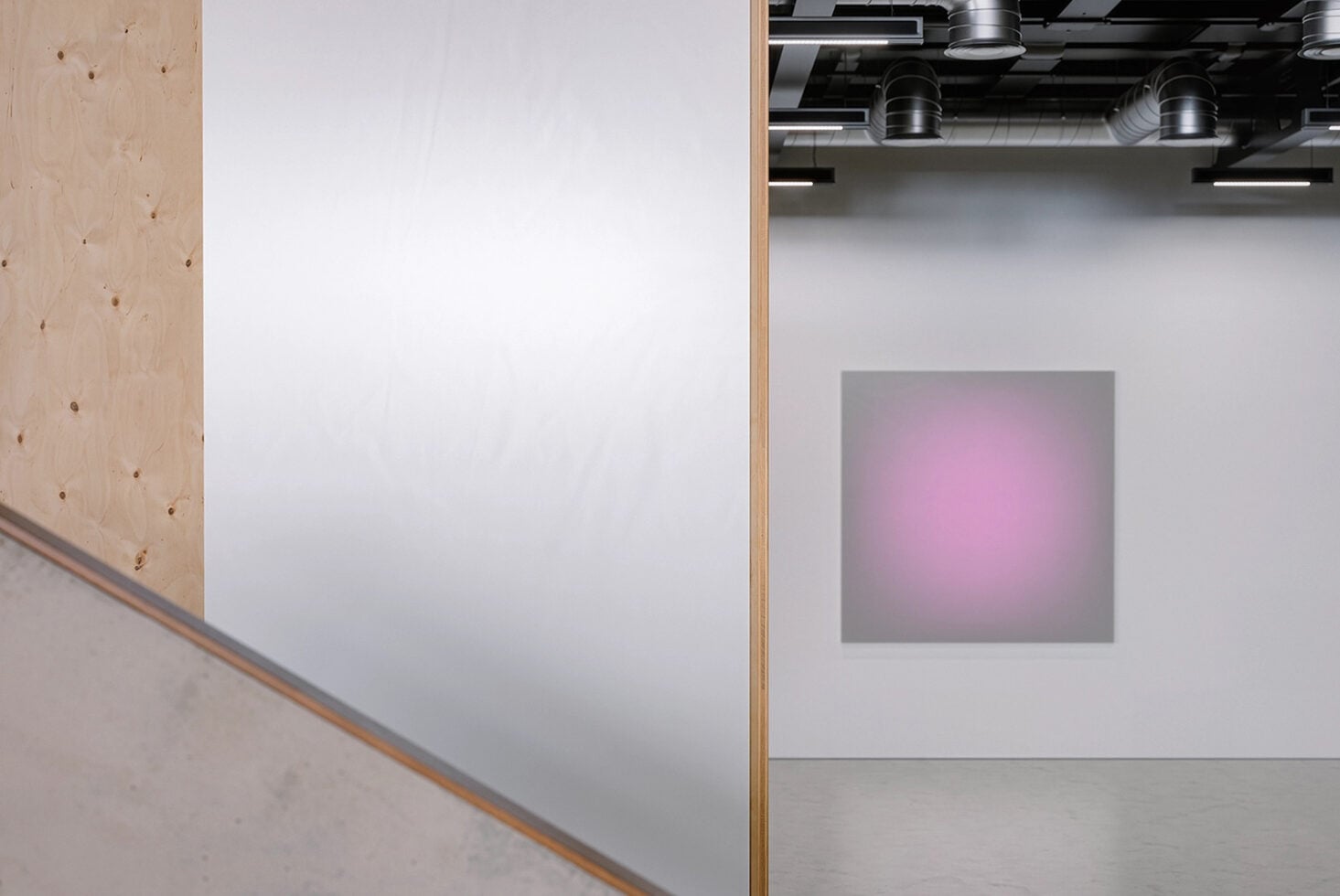 Gallery space with white canvas on wall, industrial ceiling lights