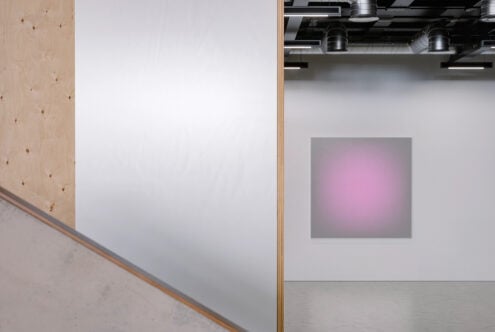 Gallery space with white canvas on wall, industrial ceiling lights