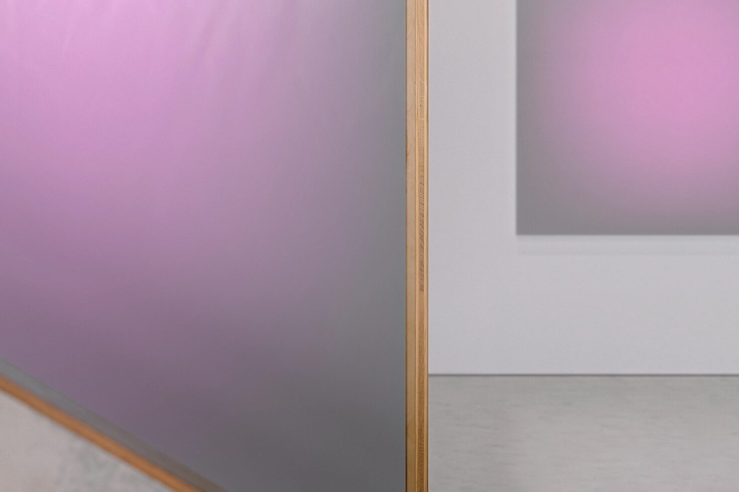 Pink gradient canvas leaning against white wall with wood frame