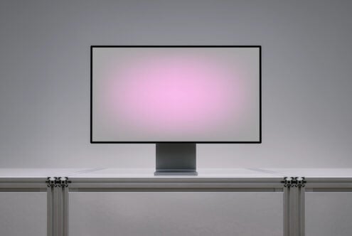 Desktop monitor mockup on desk with pink gradient screen display