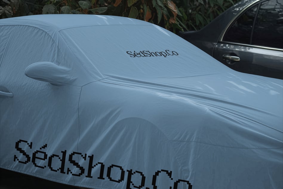 Light blue car cover with pixel-style branding mockup on sedan parked outdoors