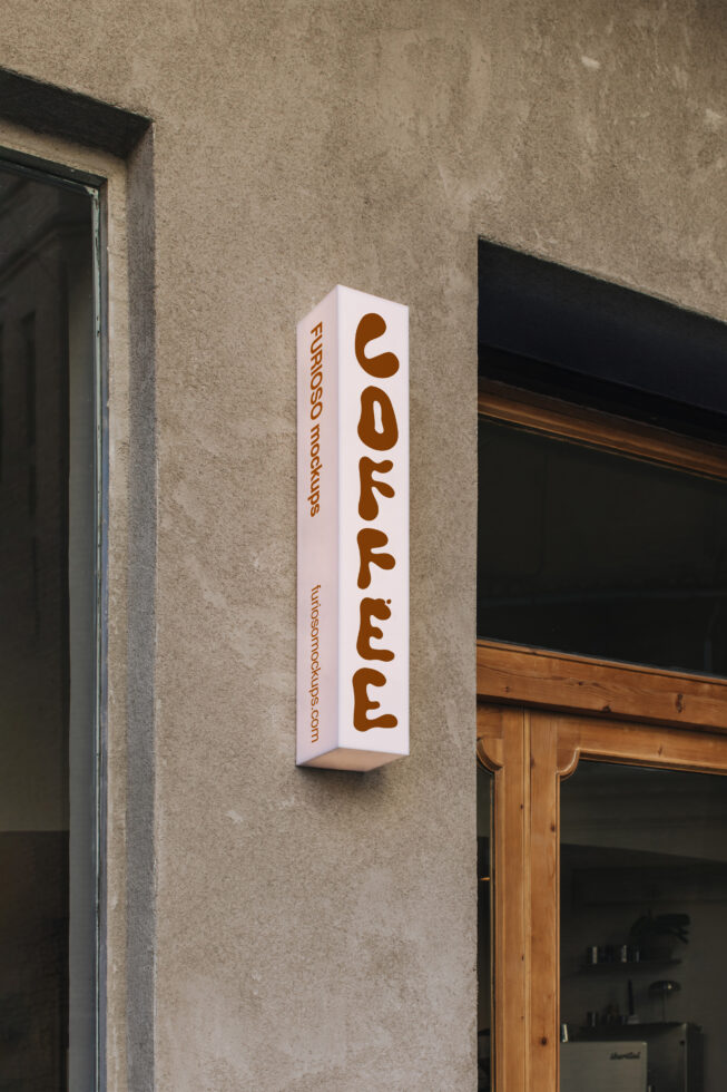 Vertical white box sign with brown rounded letters reading coffee mounted on beige facade