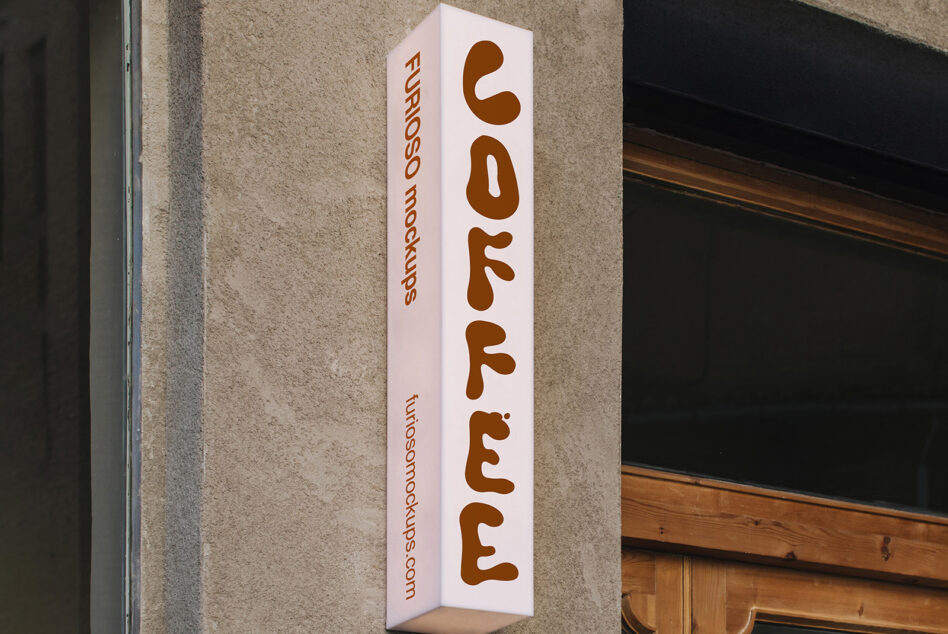 Vertical white box sign with brown rounded letters reading coffee hung on stone wall