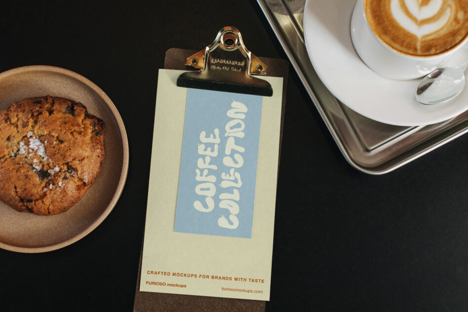 Styled overhead shot of clipboard with blue label between coffee cup latte on right, pastry bowl left
