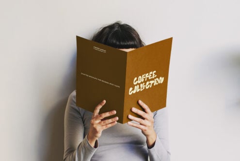 Person holding open brown folded brochure with Coffee Collection text visible