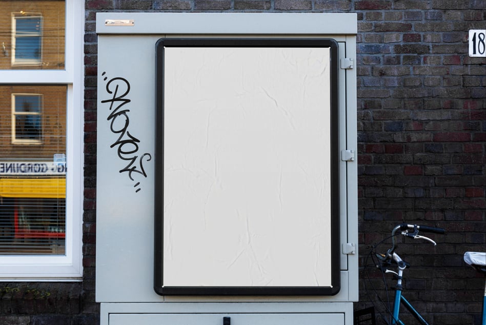Blank storefront lightbox on brick wall with graffiti tag, bike parked nearby