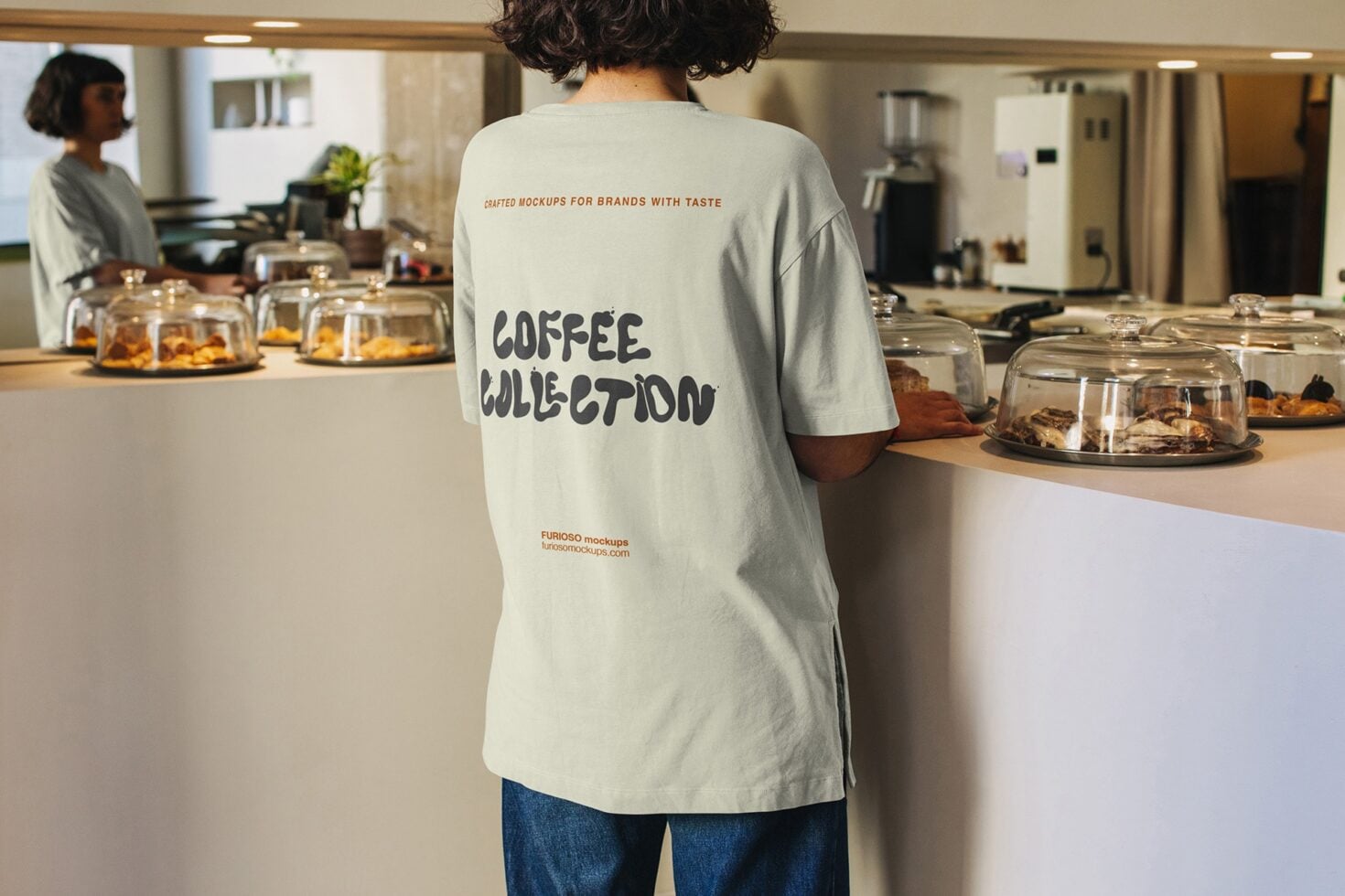 Light cream tee back view worn in cafe setting with logo visible