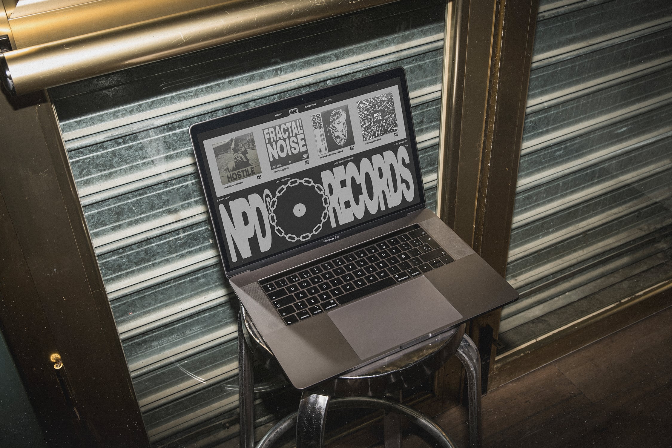 MacBook on chair displaying industrial record store website design with metal shutters