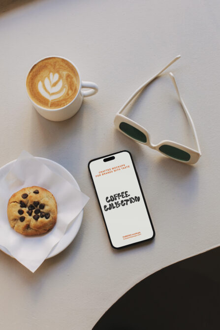 Overhead shot of iPhone mockup next to latte, cookie, white sunglasses on beige surface