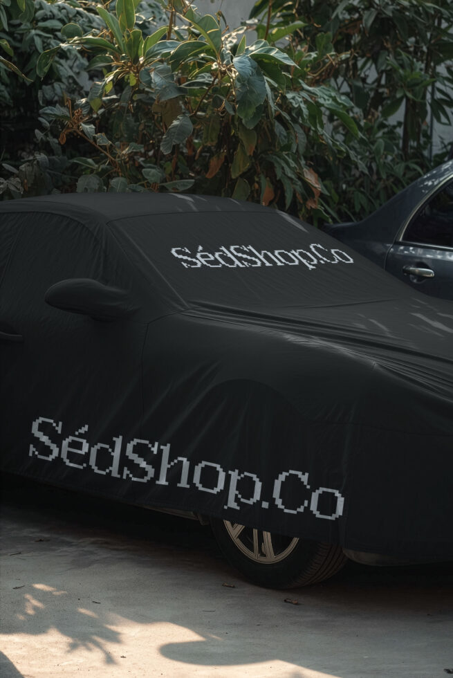 Black car cover mockup with pixelated text displayed on hood, windshield, overgrown plants backdrop