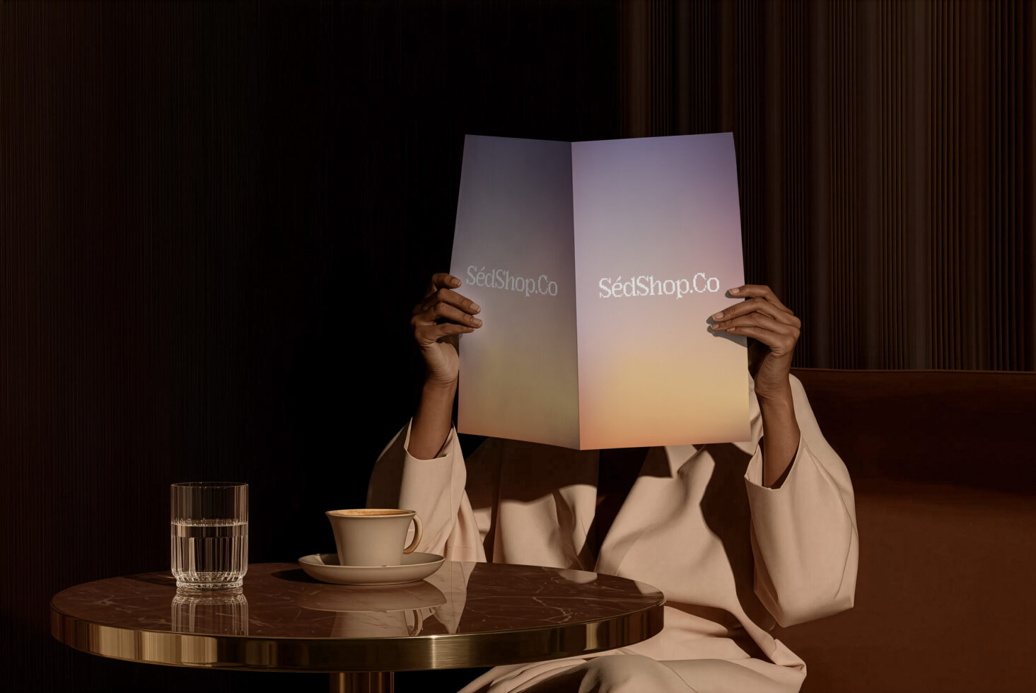 Person holding open gradient brochure mockup at table with coffee cup in moody lighting