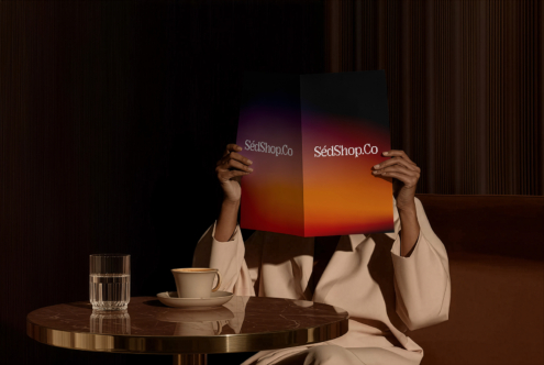 Person holding vibrant gradient mockup with SedShop.Co branding in moody interior scene
