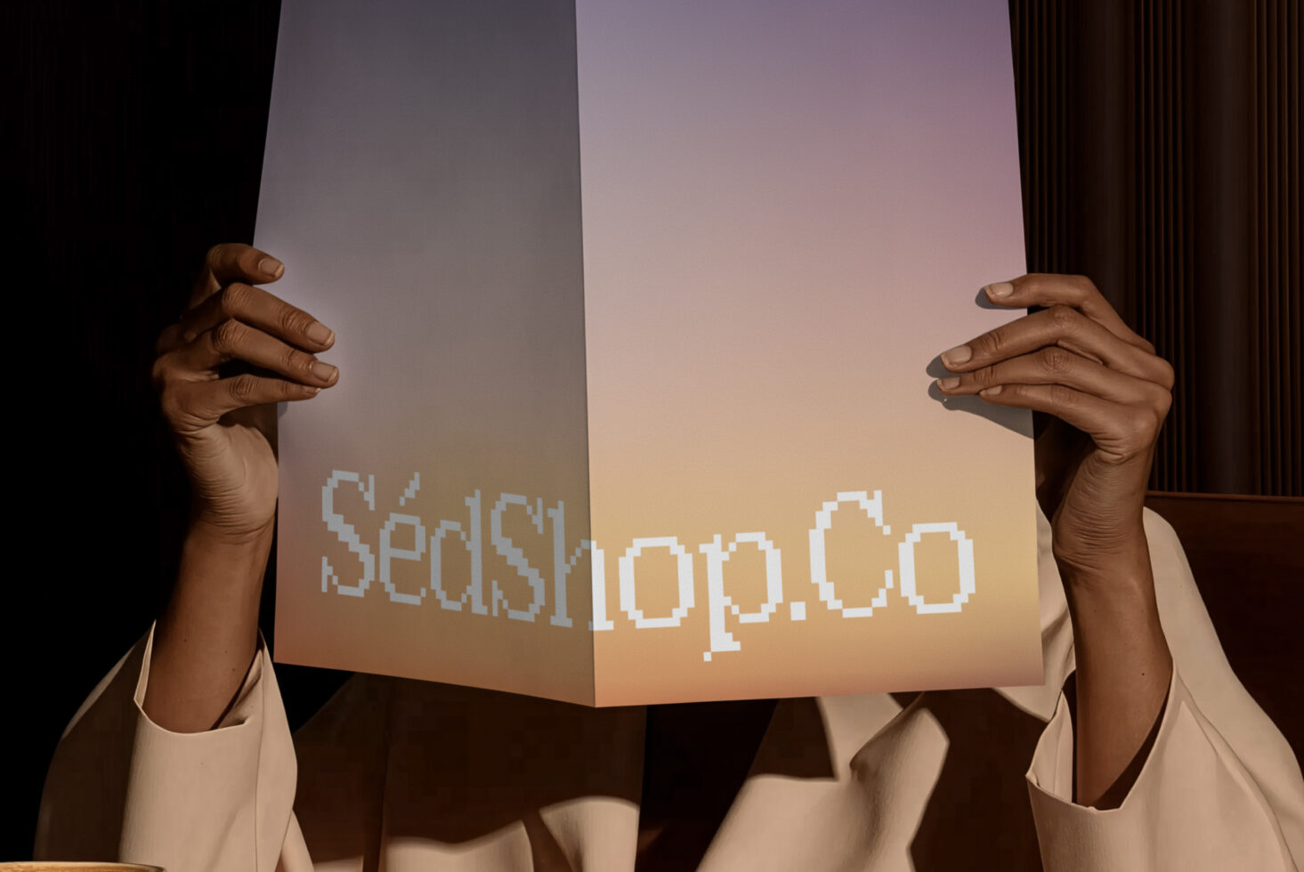 Hands holding up folded paper with pixelated SedShop.Co logo against warm gradient background
