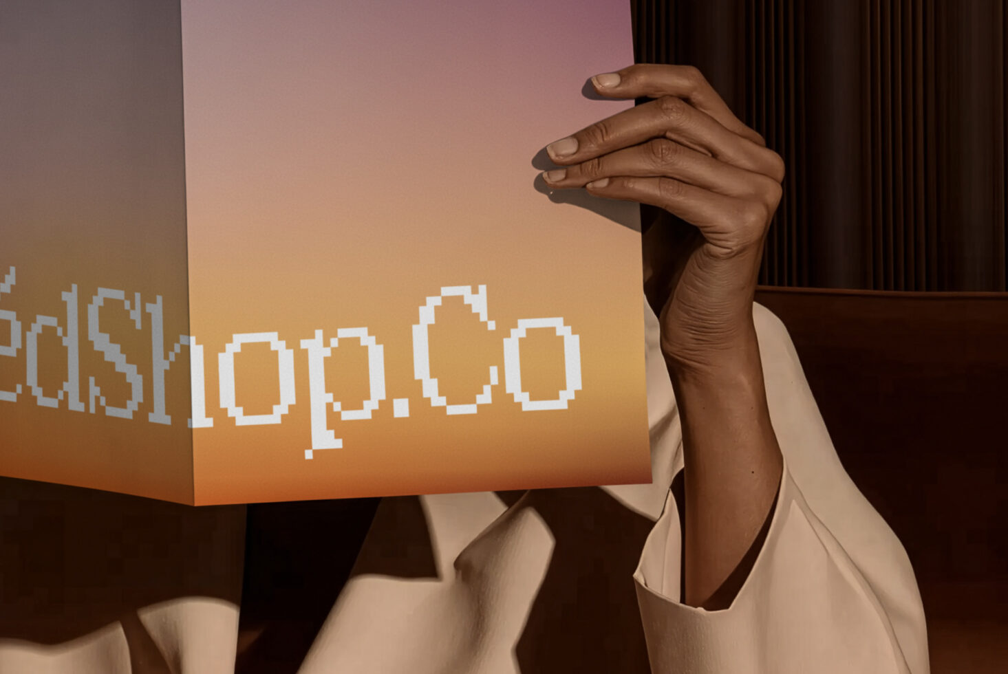 Hand holding gradient box with pixelated text on warm orange to pink background