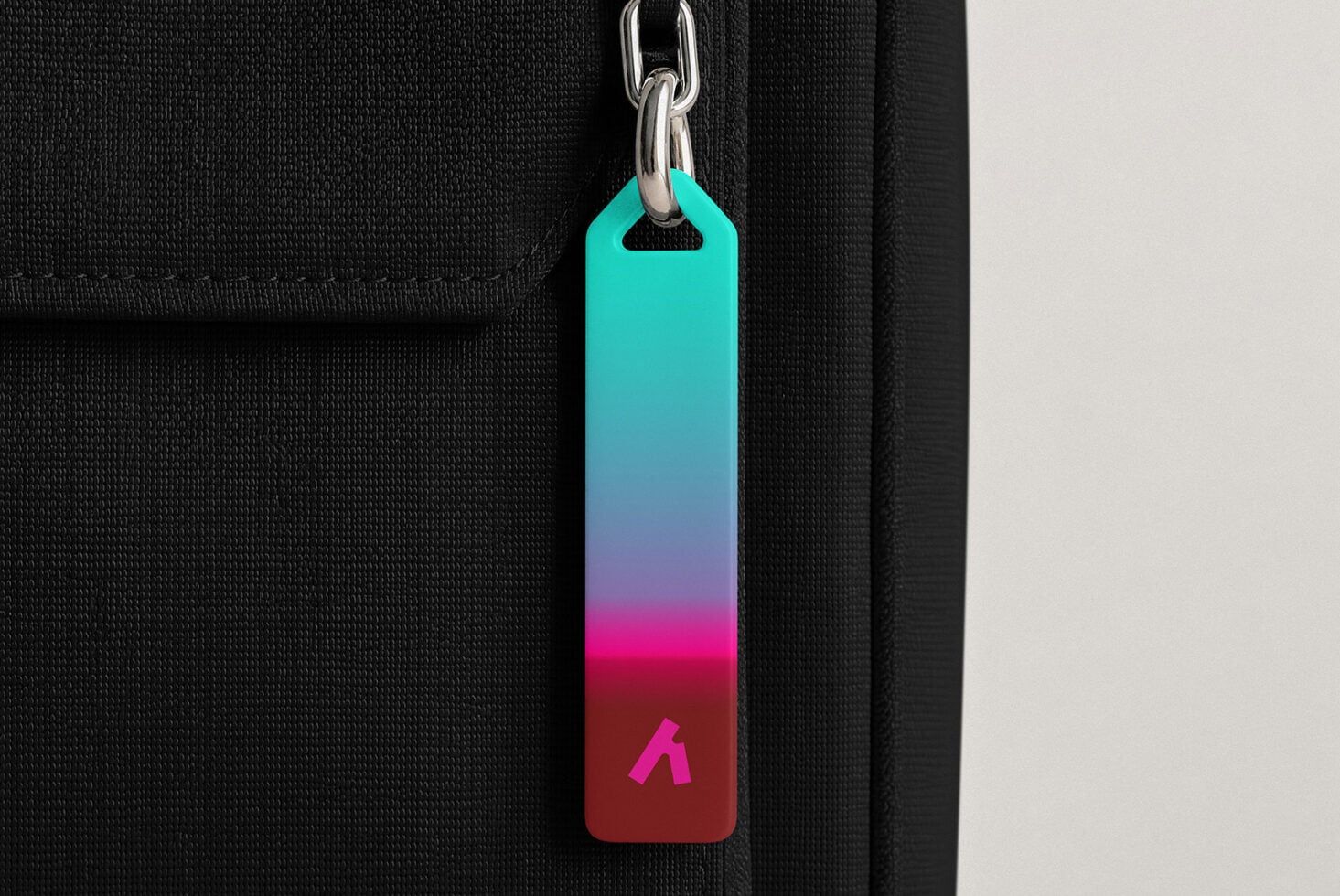Colorful gradient keychain tag hanging from silver chain on black fabric background
