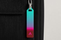 Colorful gradient keychain tag hanging from silver chain on black fabric background