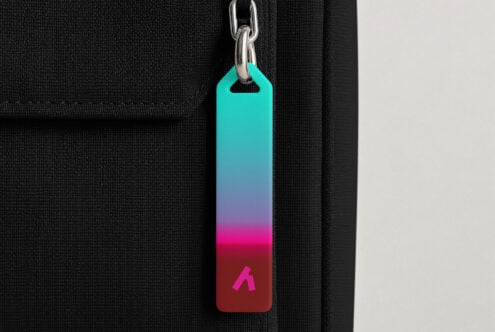 Colorful gradient keychain tag hanging from silver chain on black fabric background