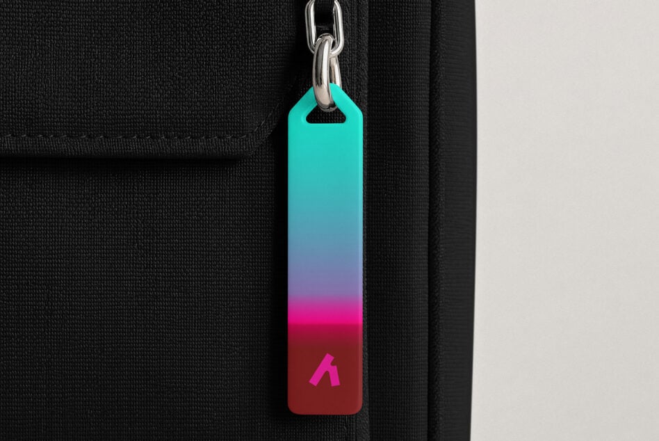 Colorful gradient keychain tag hanging from silver chain on black fabric background