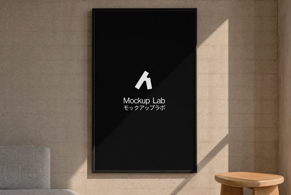 Framed poster mockup on concrete wall with natural light, wood table in corner
