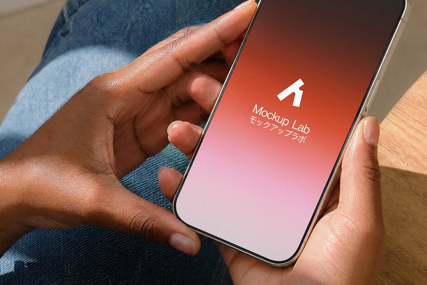 Hands holding phone with Mockup Lab app splash screen, red to pink gradient background