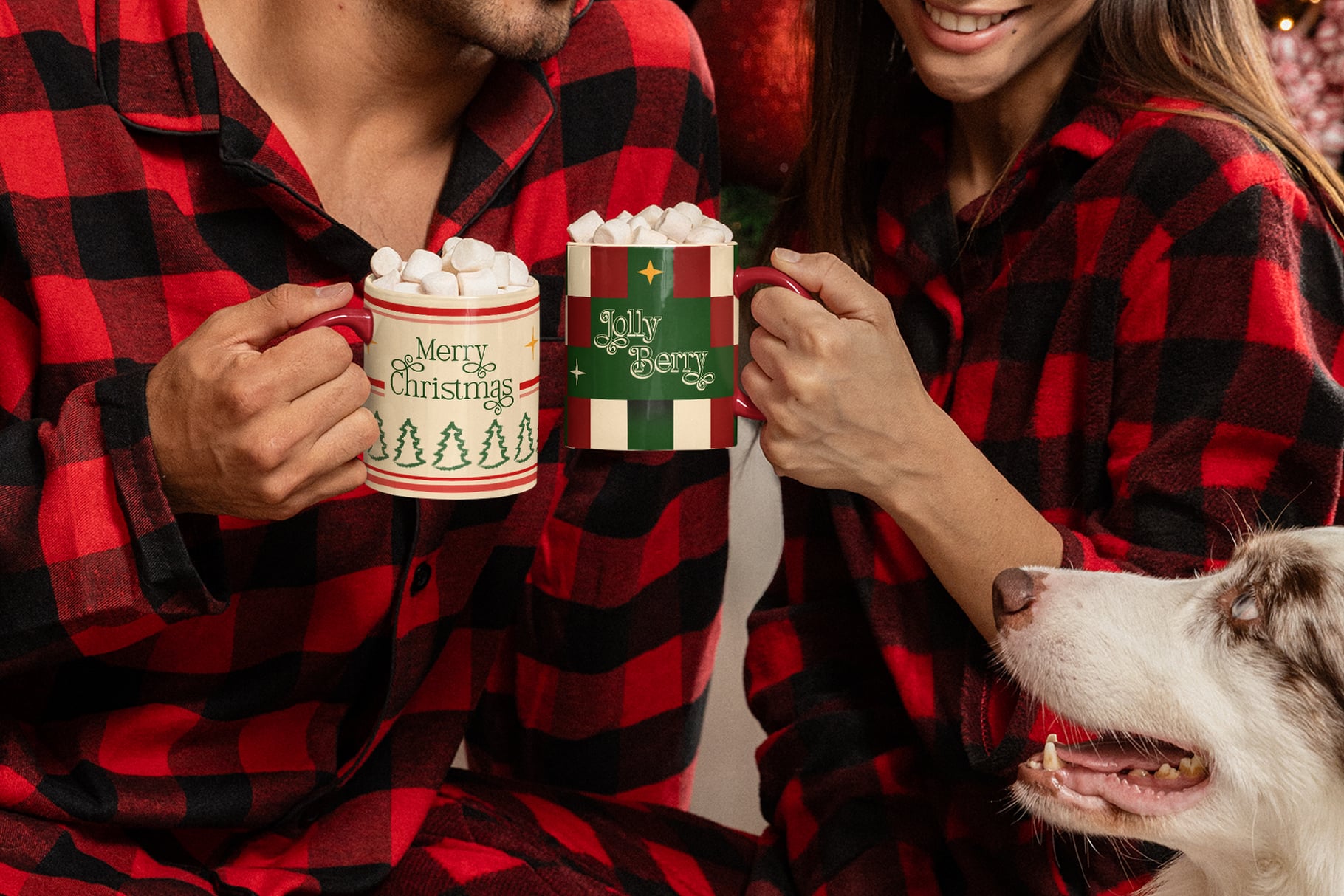 Couple in matching buffalo plaid pajamas holding festive mugs with marshmallows, small dog nearby