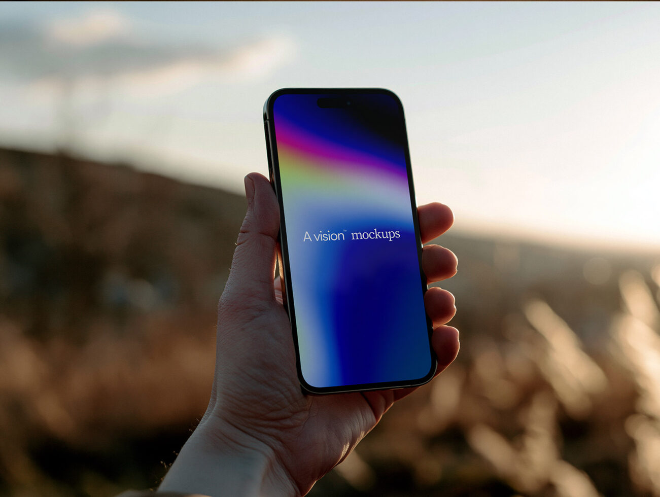 Hand holding iPhone with vibrant gradient screen in outdoor mountain setting