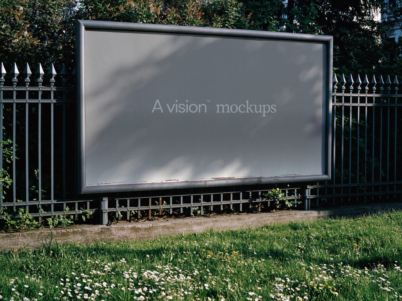 Large outdoor billboard mockup with ivy-covered fence, grass, daisies, tree shadows casting across surface