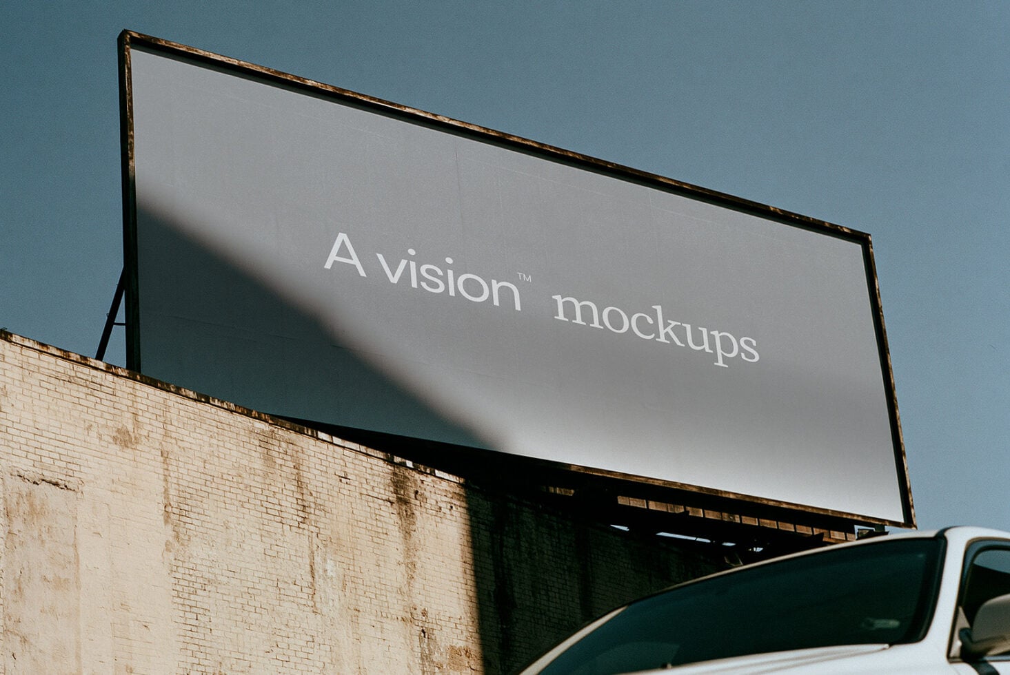 Outdoor billboard mockup with worn brick building, golden hour sunlight casting shadows across the display