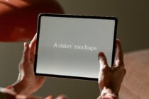 Hands holding tablet in landscape mode displaying text on neutral screen