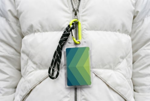 ID badge mockup on white puffer jacket with neon carabiner, green gradient design visible
