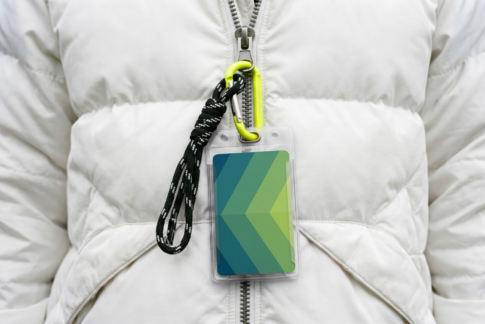 ID badge mockup on white puffer jacket with neon carabiner, green gradient design visible