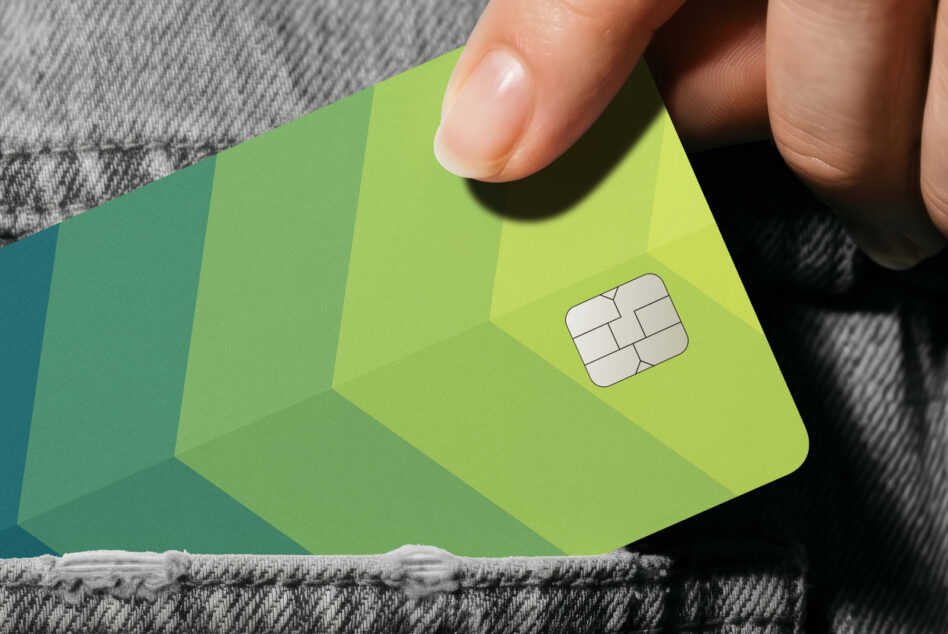 Hand holding lime green credit card with chip on fabric background
