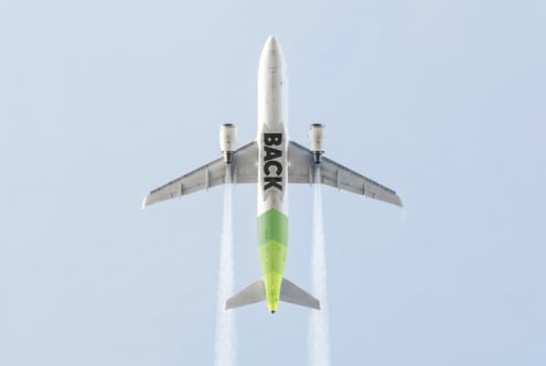 Overhead shot of white jet plane with lime green fuselage against clear sky