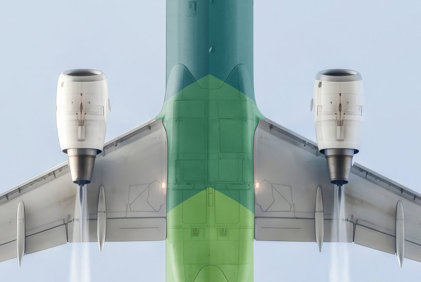 Symmetrical overhead shot of twin-engine plane with green fuselage against pale sky