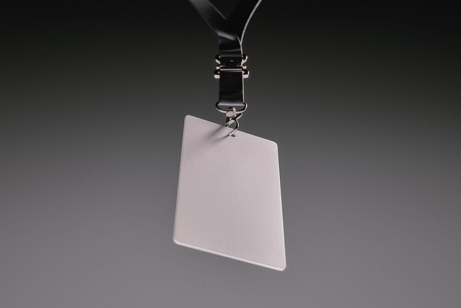 Blank ID badge hanging from black lanyard with metal clip on gray background
