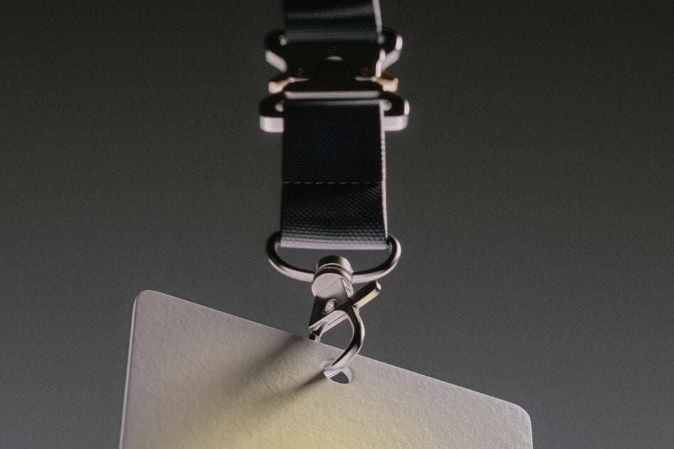 Overhead shot of black nylon bag strap with metal clasp clipped to cream canvas pouch corner