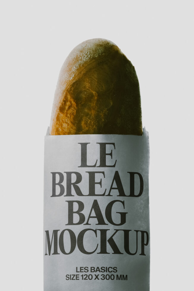 Bread bag mockup with fresh baguette poking through white label showing serif typography