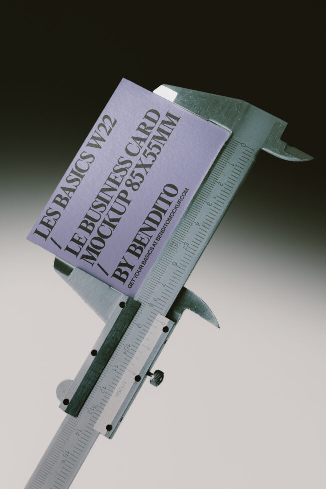 Business card mockup clamped in digital caliper with measurement scale visible
