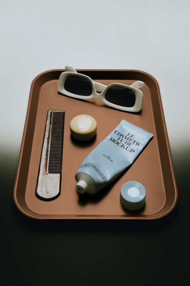 Cosmetic tube mockup with sunglasses, comb, jars on tan tray