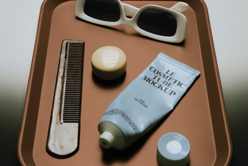 Cream tube mockup on terracotta tray with sunglasses, comb, jar, plus two cream containers styled flat lay
