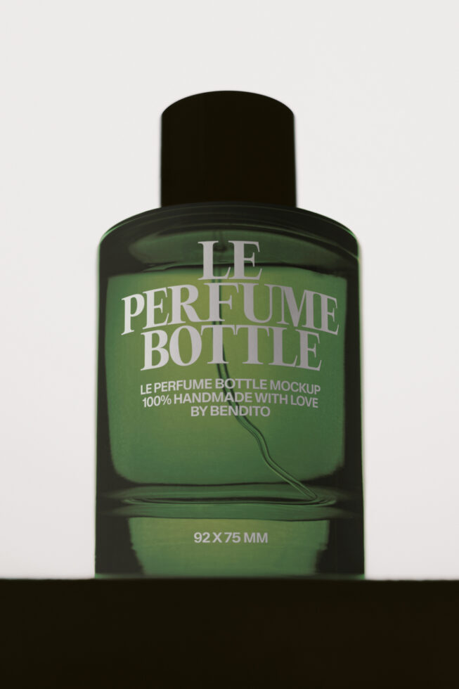 Green perfume bottle mockup with black cap, handmade branding label on neutral background