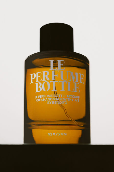Luxury perfume bottle mockup with black cap, amber glass, white serif typography on golden label