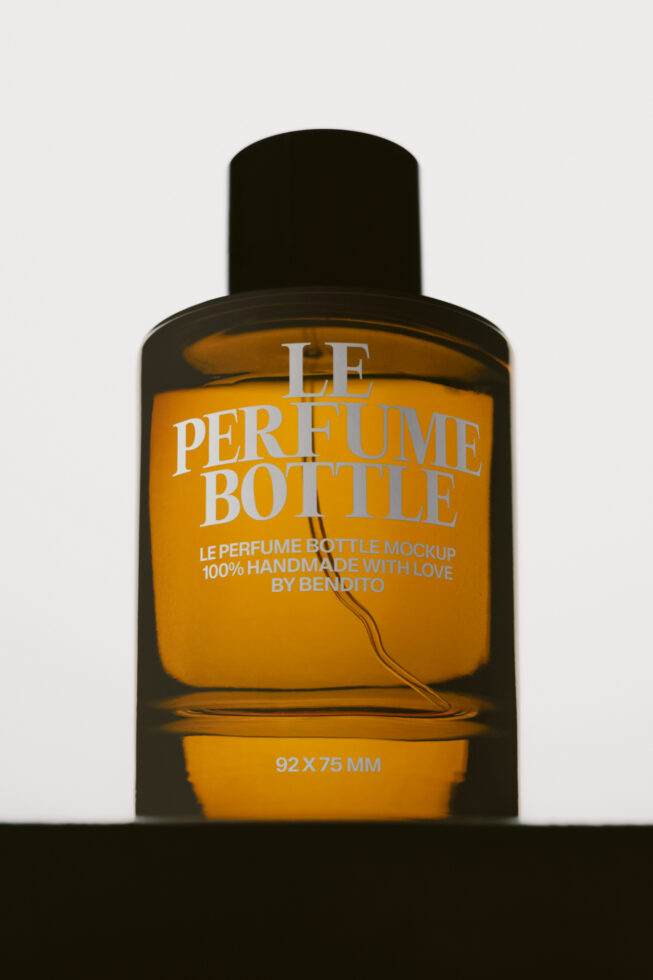 Luxury perfume bottle mockup with black cap, amber glass, white serif typography on golden label