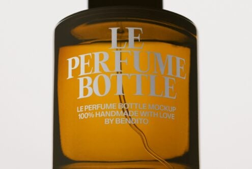 Luxury perfume bottle mockup with gold label on dark glass container showing customizable branding space