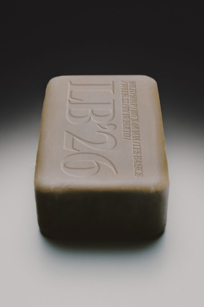 Handmade soap bar with embossed logo on top, natural beige color, rounded edges, studio shot on neutral background