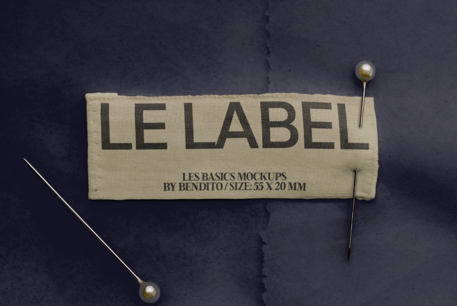 Cream fabric label pinned to dark background with gold pearl-head pins