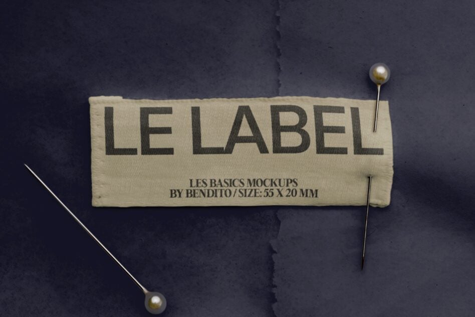 Cream fabric label pinned to dark background with gold pearl-head pins