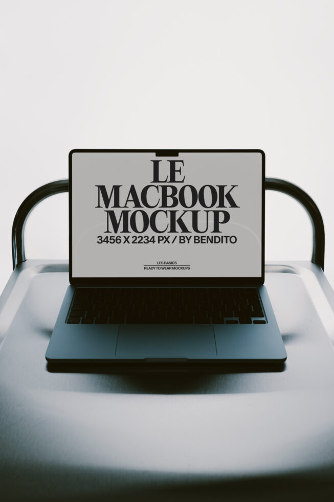 MacBook mockup on white chair with black frame, screen showing typography layout