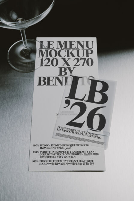 Martini glass next to layered menu mockups with bold serif typography on metallic surface